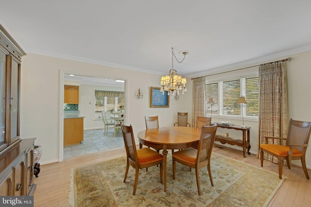 dining area with an inviting chandelier, crown molding, and light wood-type flooring