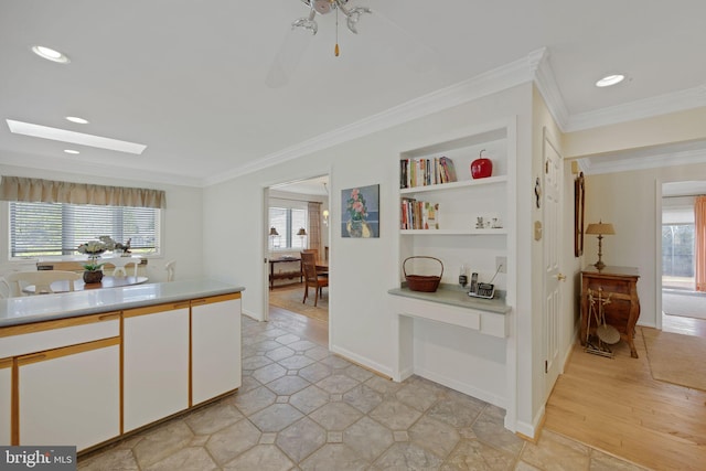 hallway featuring crown molding, a skylight, and built in shelves