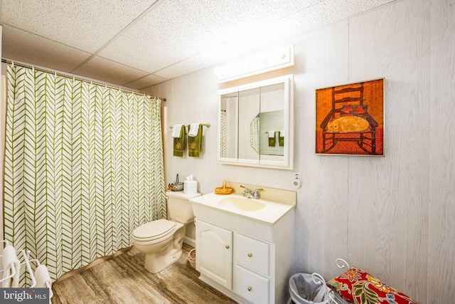 bathroom featuring hardwood / wood-style flooring, a shower with shower curtain, vanity, a drop ceiling, and toilet