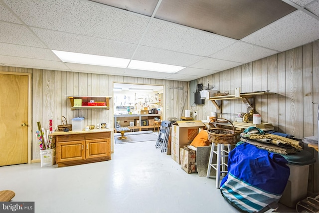 interior space with a drop ceiling and wooden walls