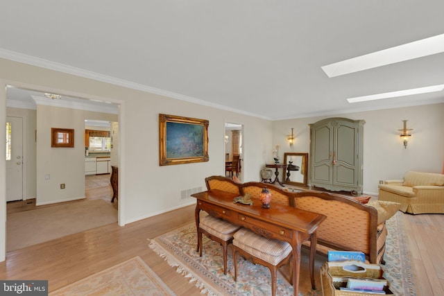 dining space featuring crown molding, light hardwood / wood-style floors, and a skylight