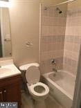 full bathroom featuring vanity, tiled shower / bath combo, and toilet