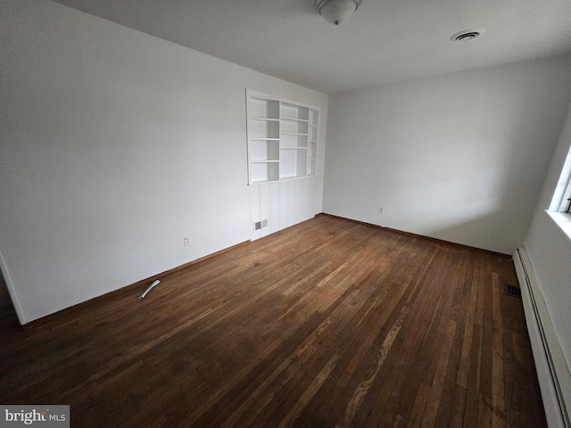 unfurnished room featuring dark hardwood / wood-style flooring, built in shelves, and a baseboard radiator