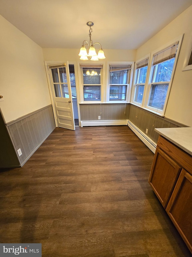 unfurnished dining area with a notable chandelier, dark hardwood / wood-style floors, and baseboard heating