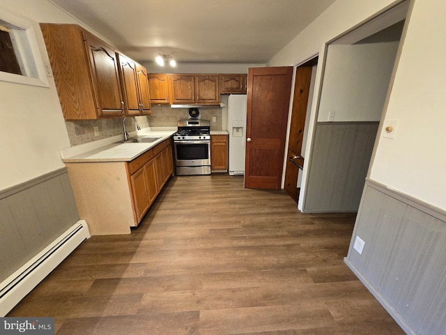 kitchen featuring sink, baseboard heating, hardwood / wood-style floors, white fridge with ice dispenser, and stainless steel range with gas cooktop