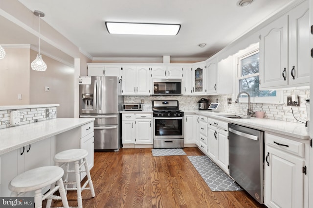 kitchen featuring appliances with stainless steel finishes, sink, hanging light fixtures, and white cabinets