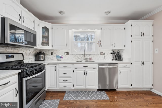 kitchen with appliances with stainless steel finishes, dark hardwood / wood-style floors, sink, backsplash, and white cabinets