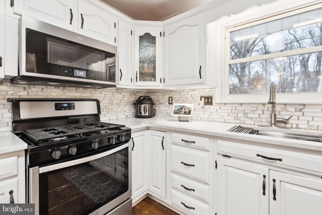 kitchen featuring stainless steel appliances, white cabinetry, sink, and tasteful backsplash