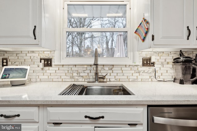 kitchen featuring sink, white cabinets, light stone counters, and decorative backsplash