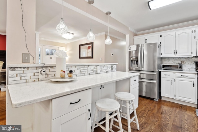 kitchen with light stone countertops, pendant lighting, white cabinets, and stainless steel fridge with ice dispenser