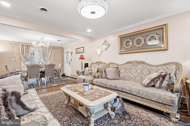 living room featuring hardwood / wood-style flooring, ornamental molding, and an inviting chandelier