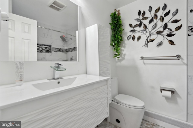 bathroom with vanity, a tile shower, and toilet