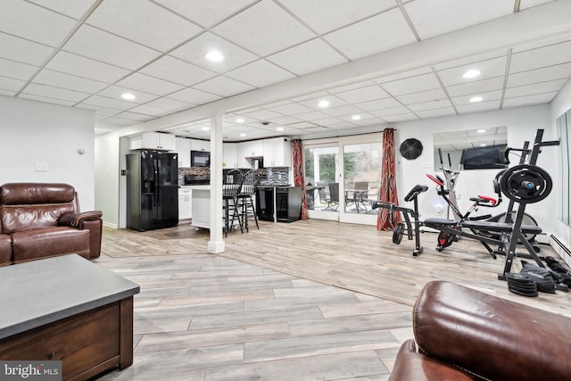 workout room featuring a paneled ceiling and light wood-type flooring