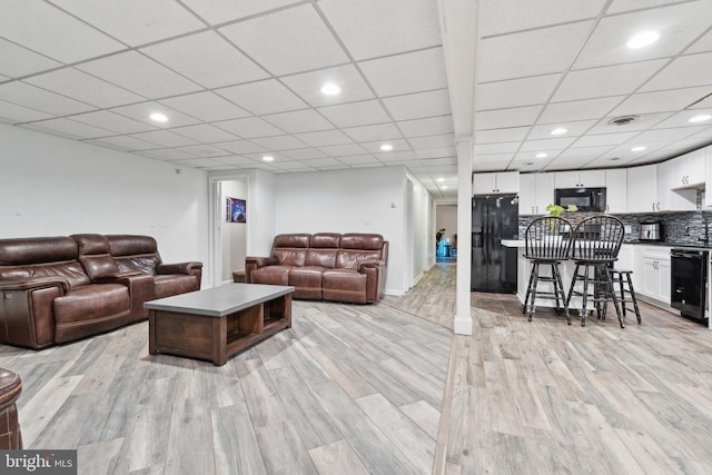 living room with wine cooler, light hardwood / wood-style flooring, and a drop ceiling