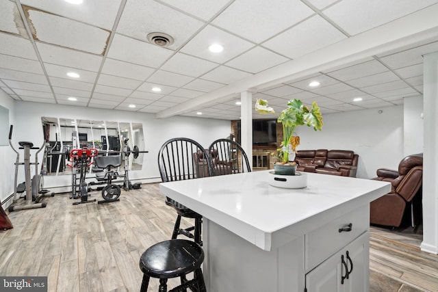 kitchen with a breakfast bar area, a center island, white cabinets, and light wood-type flooring