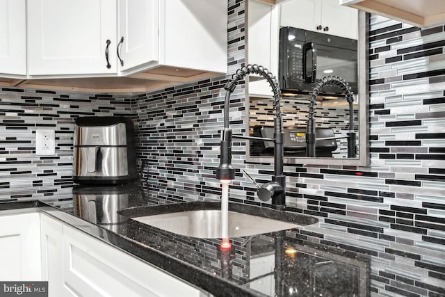 kitchen with tasteful backsplash, white cabinets, and dark stone counters