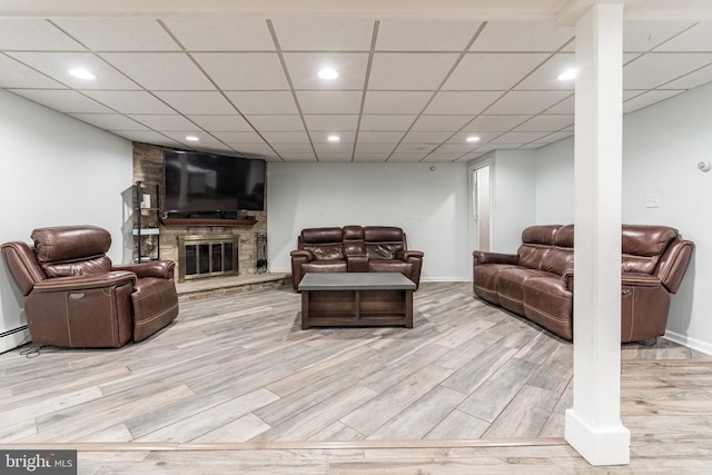 living room featuring a fireplace, a paneled ceiling, and light wood-type flooring