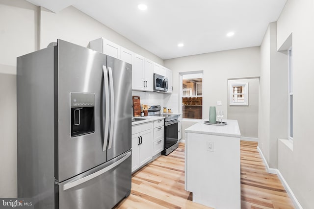 kitchen featuring white cabinets, decorative backsplash, a center island, stainless steel appliances, and light hardwood / wood-style flooring