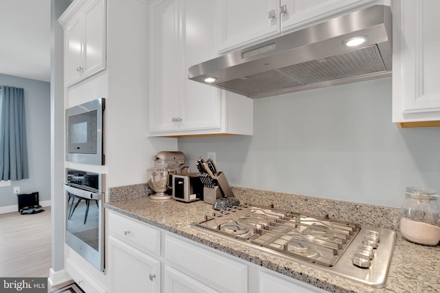 10056 American Pharoah Ln Unit 66, Laurel, MD 20723 - kitchen featuring under cabinet range hood, appliances with stainless steel finishes, white cabinets, baseboards, and light stone counters