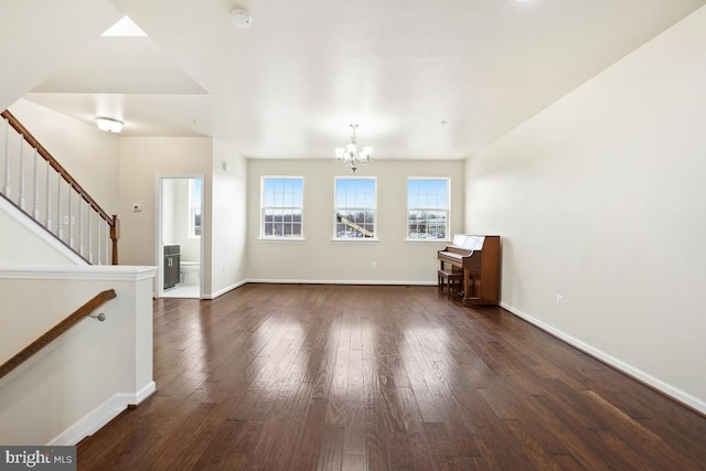 unfurnished living room featuring a chandelier, dark wood finished floors, stairs, and baseboards