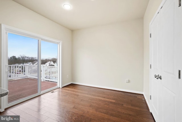 unfurnished room featuring baseboards, visible vents, and wood finished floors