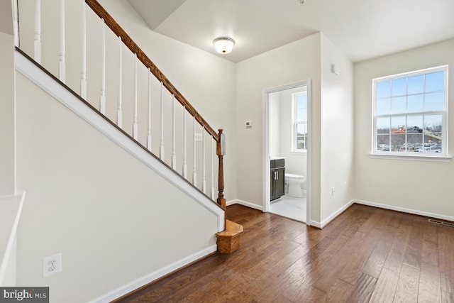 foyer entrance featuring baseboards, visible vents, stairway, and dark wood finished floors