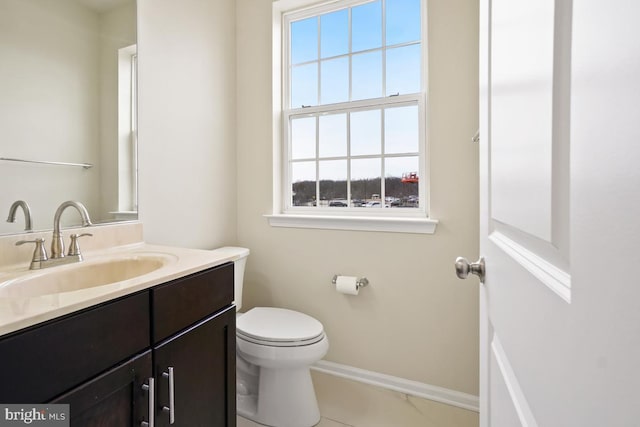 half bathroom with toilet, vanity, and baseboards