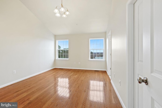 interior space with baseboards, light wood finished floors, lofted ceiling, and a notable chandelier