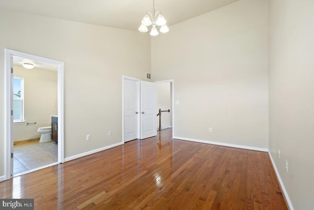 unfurnished bedroom featuring a notable chandelier, wood finished floors, and baseboards