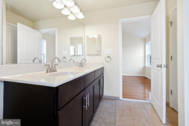 bathroom with double vanity, tile patterned flooring, a sink, and baseboards