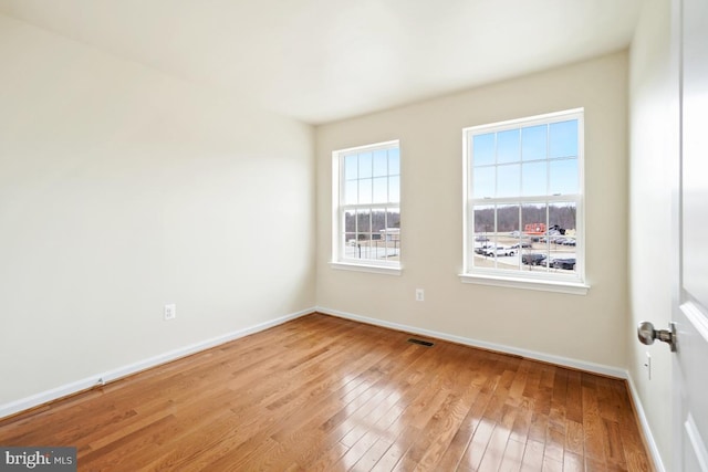 unfurnished room featuring light wood-type flooring, baseboards, and visible vents