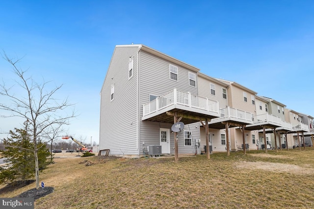 rear view of property with central AC unit and a lawn