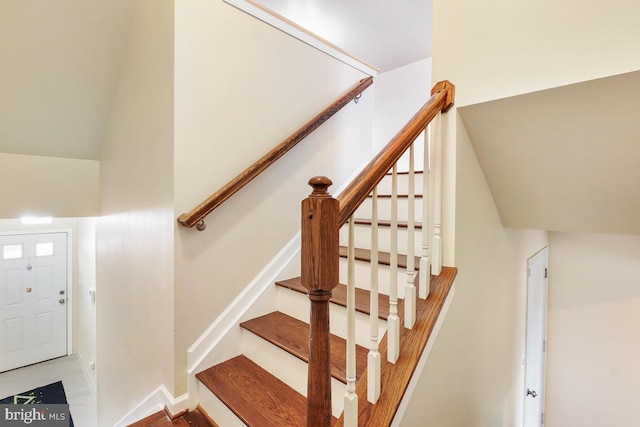 stairway with vaulted ceiling and baseboards