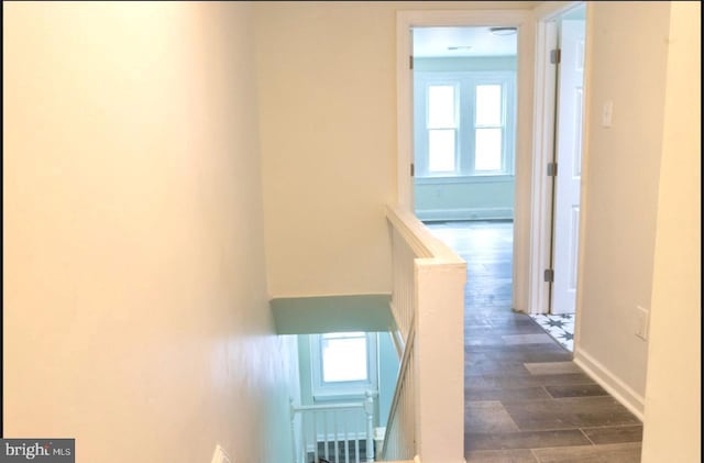 hall with an upstairs landing, dark wood finished floors, and baseboards