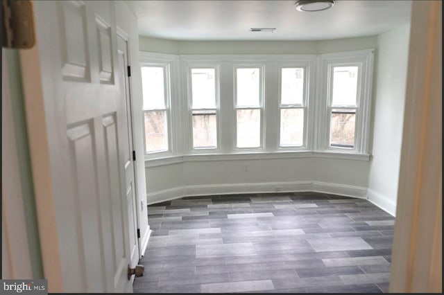 unfurnished room featuring dark wood-style floors, baseboards, and visible vents