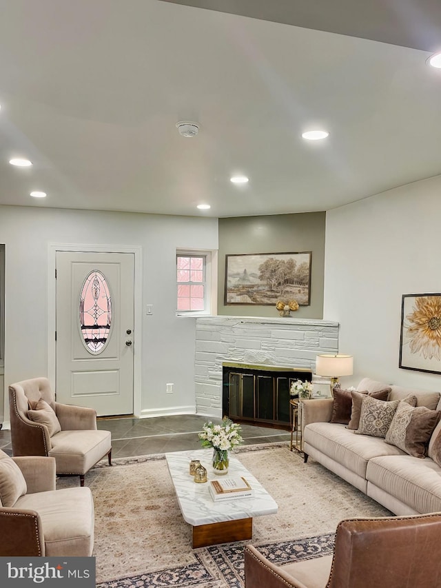 living area featuring a stone fireplace, recessed lighting, and baseboards