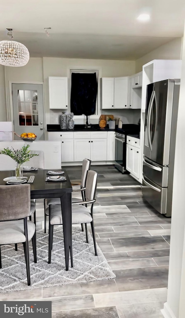 kitchen with white cabinetry, dark countertops, wood finish floors, and stainless steel appliances