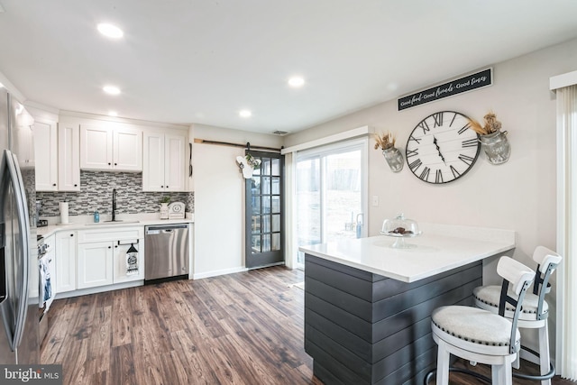 kitchen featuring sink, a breakfast bar, appliances with stainless steel finishes, white cabinets, and dark hardwood / wood-style flooring