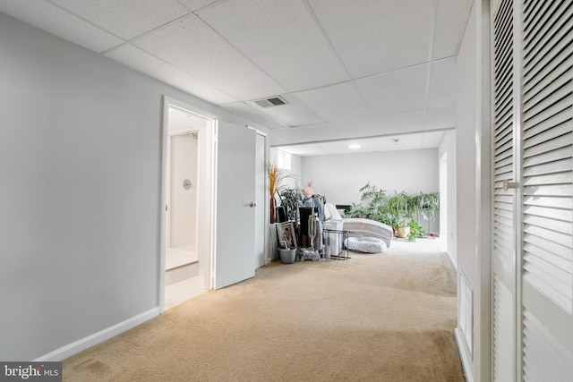 hall with a paneled ceiling, visible vents, baseboards, and carpet