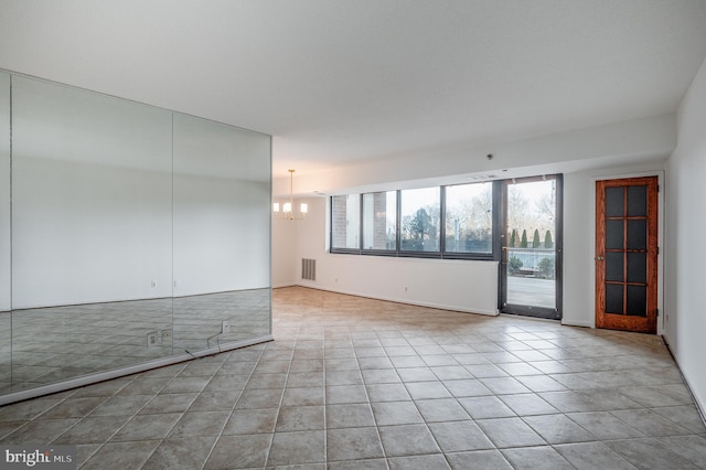 spare room featuring a chandelier and light tile patterned floors