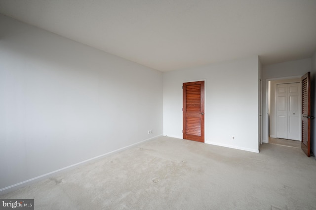 unfurnished bedroom with light colored carpet and a closet