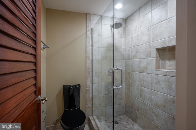 bathroom featuring toilet and a shower with door