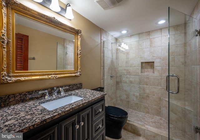 bathroom featuring vanity, a shower with shower door, and toilet