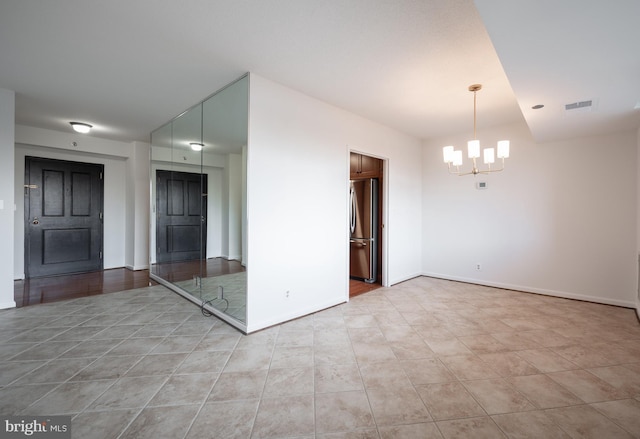 unfurnished room with a notable chandelier