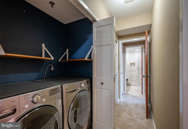 clothes washing area featuring washing machine and clothes dryer, a textured ceiling, and light tile patterned floors