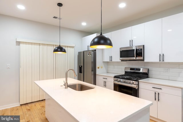 kitchen featuring white cabinetry, hanging light fixtures, stainless steel appliances, and sink