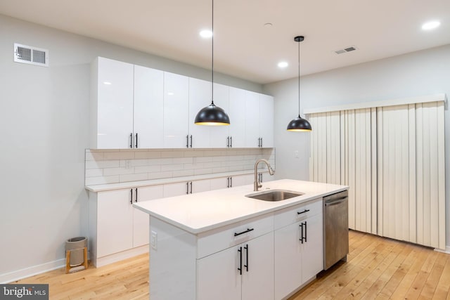 kitchen with sink, dishwasher, a kitchen island with sink, white cabinets, and decorative light fixtures