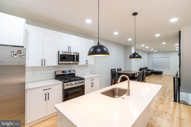 kitchen featuring sink, white cabinetry, hanging light fixtures, backsplash, and stainless steel appliances