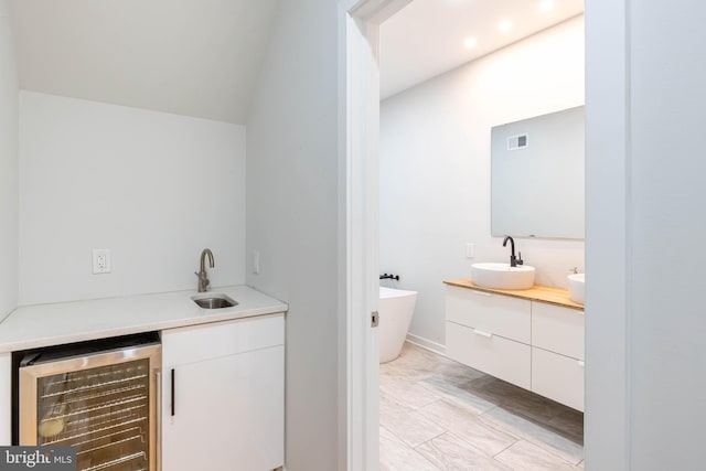 bathroom with vanity, a tub to relax in, lofted ceiling, and beverage cooler