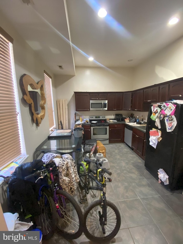 kitchen featuring light tile patterned flooring, stainless steel appliances, and dark brown cabinets